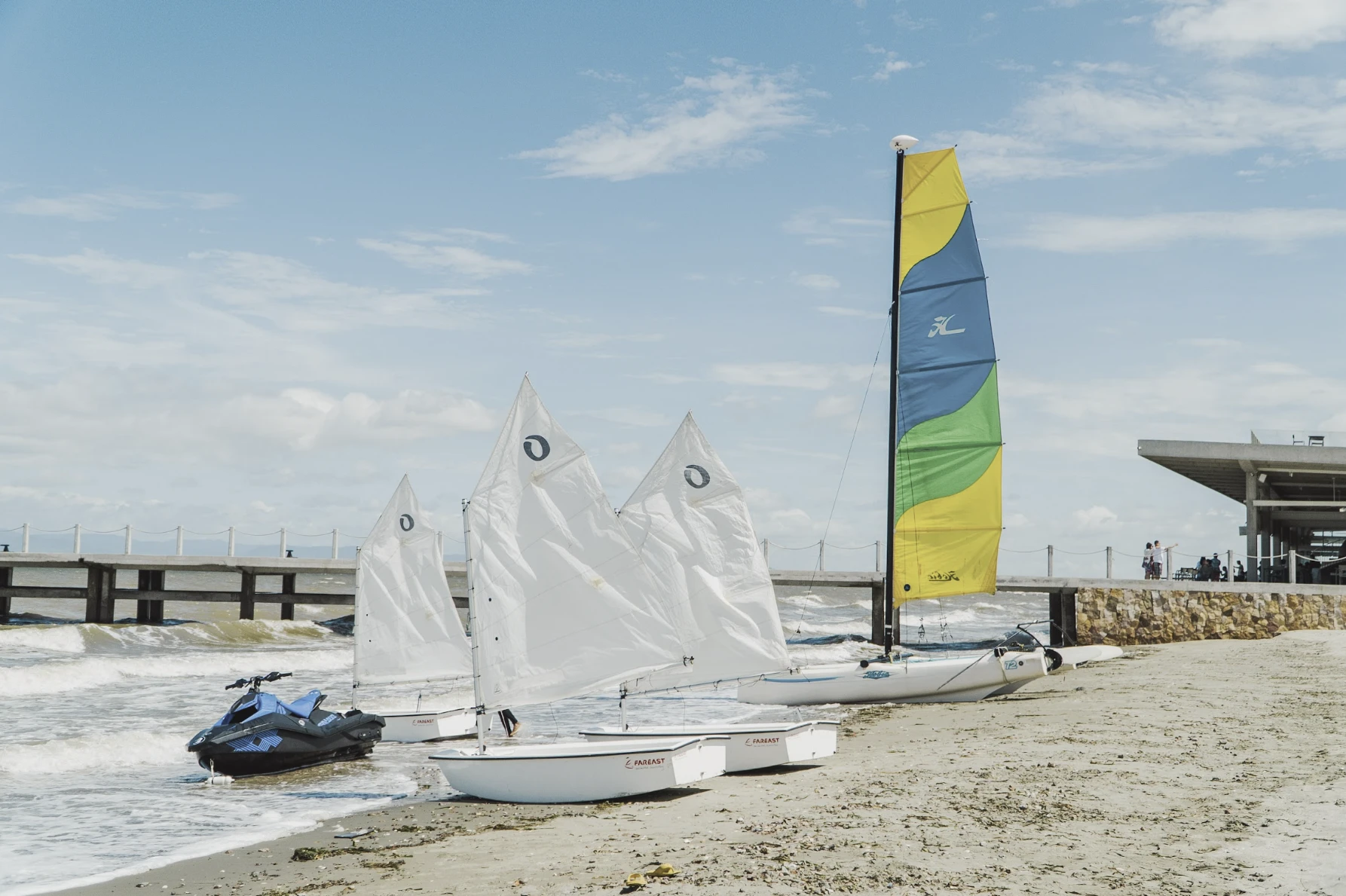 Sailing dinghies, a catamaran and a jet ski on the beach at Kep West